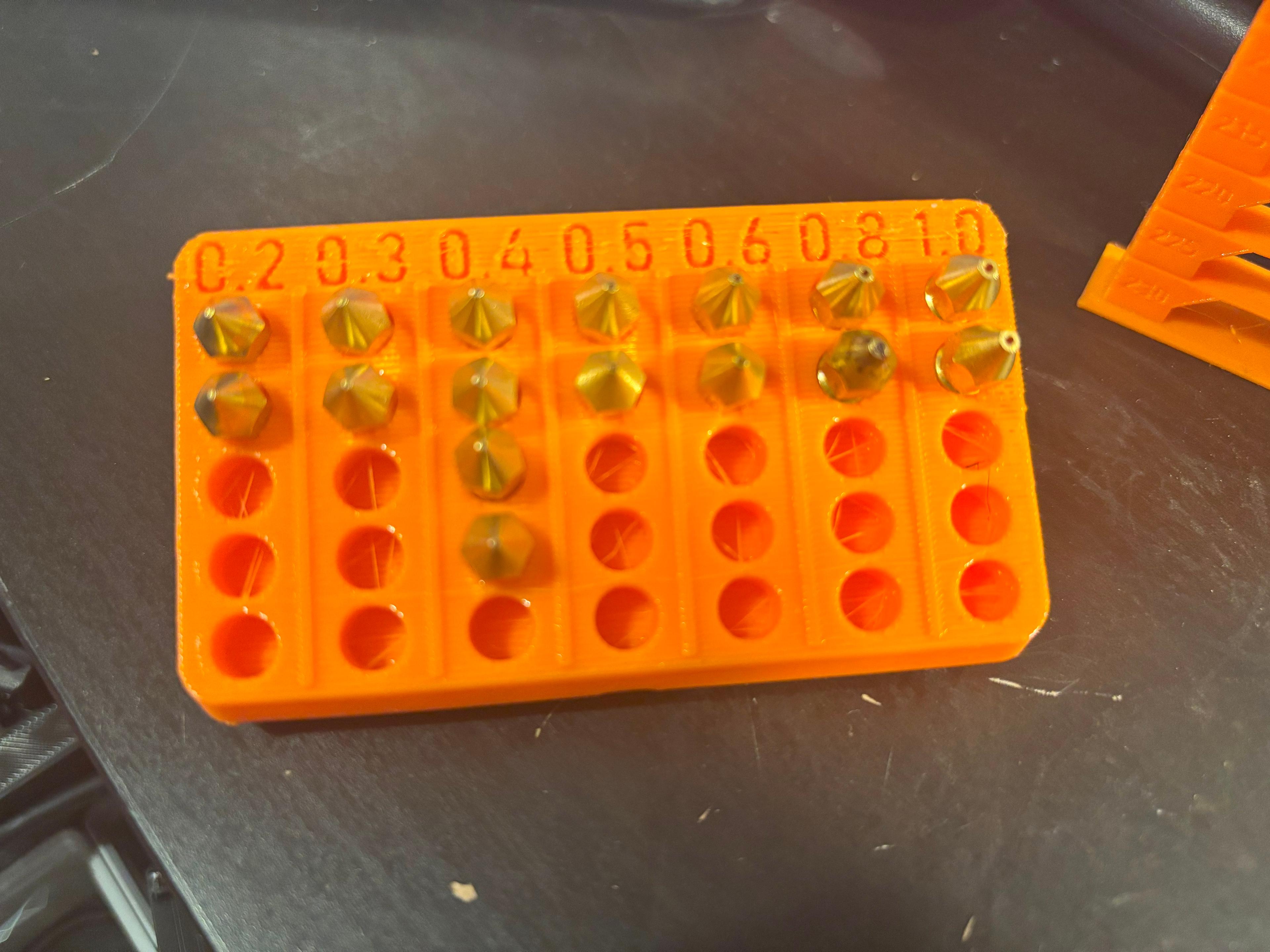 Gridfinity Nozzle holder for most common sizes - Printed at 225C with eSun Orange PLA+.  Slight bit of stringing in the holes and over the numbers, but easily cleaned up.  Perfect for my nozzles. - 3d model