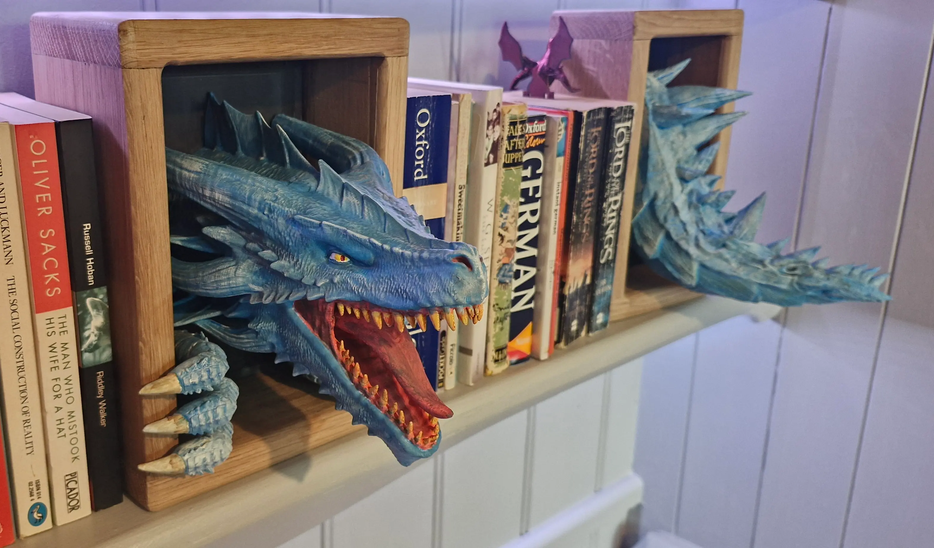 Another Fantastic Print - Awakening Dragon with a Twist!
Hi Crafty Kid,
I just wanted to share another successful and enjoyable print using one of your fantastic models! Following up on the Emerging Dragon I made previously, I recently printed your Awakening Dragon for my youngest son's girlfriend.
She has some open shelving for her books, so I decided to create some sturdy oak bookends for her. Let's just say they're built to last!
To personalise the Awakening Dragon and inspired by a book she owns featuring an Ice Dragon, I decided on a similar colour scheme and even incorporated the tail from your Emerging Dragon design. It worked out perfectly!
I'm still developing my painting skills, but I had a wonderful time bringing this model to life. Thanks again for creating such well-designed and printable files.
Best regards,
Trickyhicky