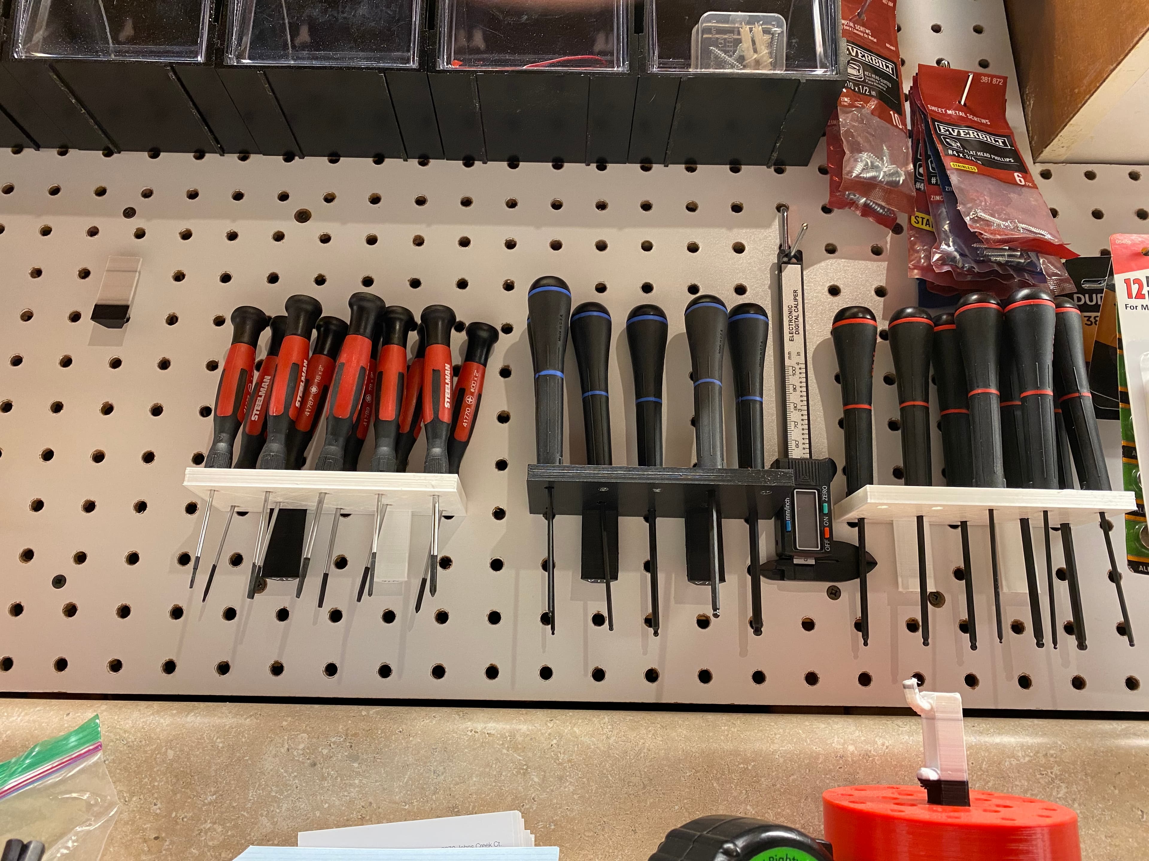 Plank.stl - bottom view of tool holders and pegBlock.stl on 1/4" pegboard. Note peg block on top of red cylinder bottom right - 3d model