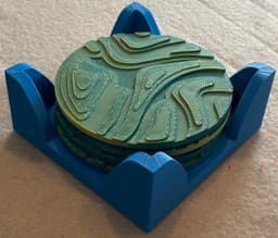 Coasters were printed with Amolen Dual Color PLA in blue and yellow with the holder printed in Bambu PLA in blue. The two colors blended to a medium green with blue and yellow highlights. Cork disks were added to the bottom of the coasters and holder for stability. 3d model