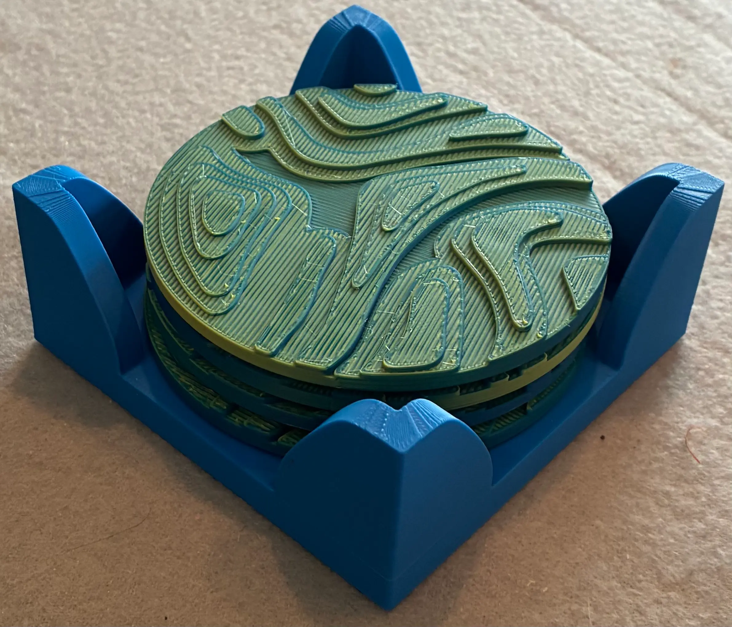 Coasters were printed with Amolen Dual Color PLA in blue and yellow with the holder printed in Bambu PLA in blue. The two colors blended to a medium green with blue and yellow highlights. Cork disks were added to the bottom of the coasters and holder for stability.